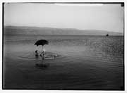 Photograph of a man floating and reading a book in the Dead Sea